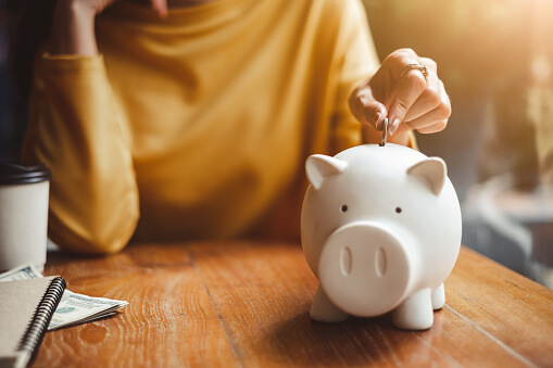 Image of woman putting money in piggy bank
